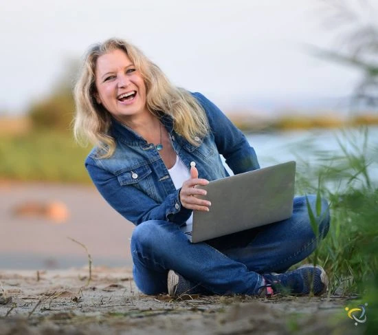 christiane sternberger lachend mit laptop am elbestrand 